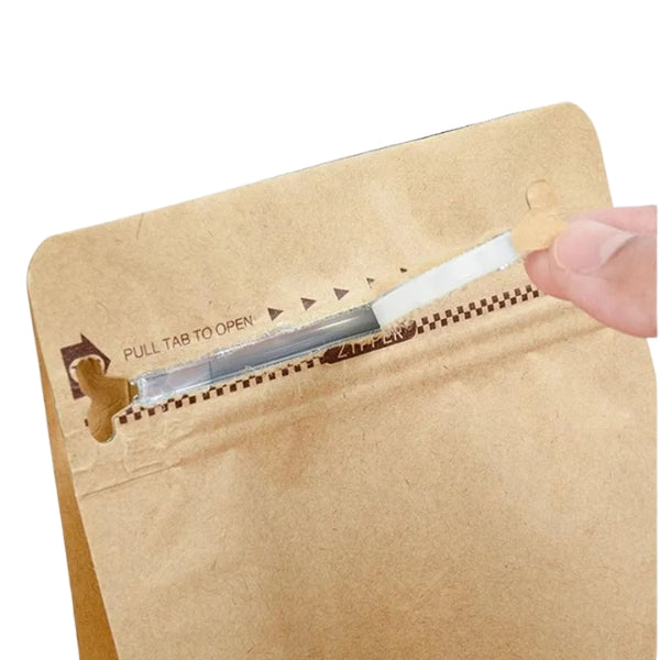 Kraft paper bag with a pull tab being used to open it on a white background